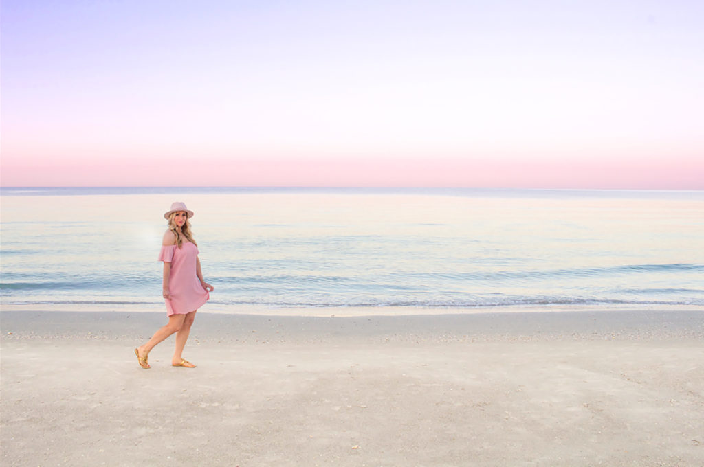 A Woman walking at the beach with wearing a hat