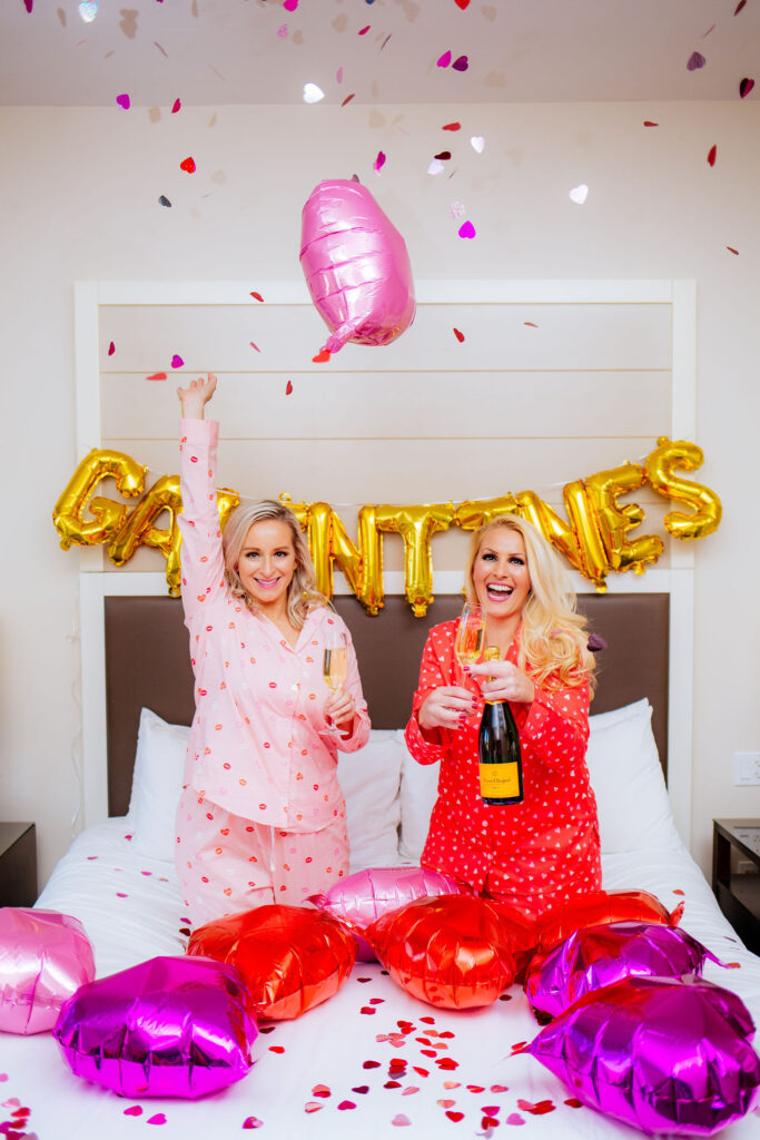 St. Pete Blogger, Jill DiGioia of The Lovely Flamingo celebrates Galentine's Day in heart pajamas throwing confetti and balloons at the Epicurean Hotel in Tampa Florida.