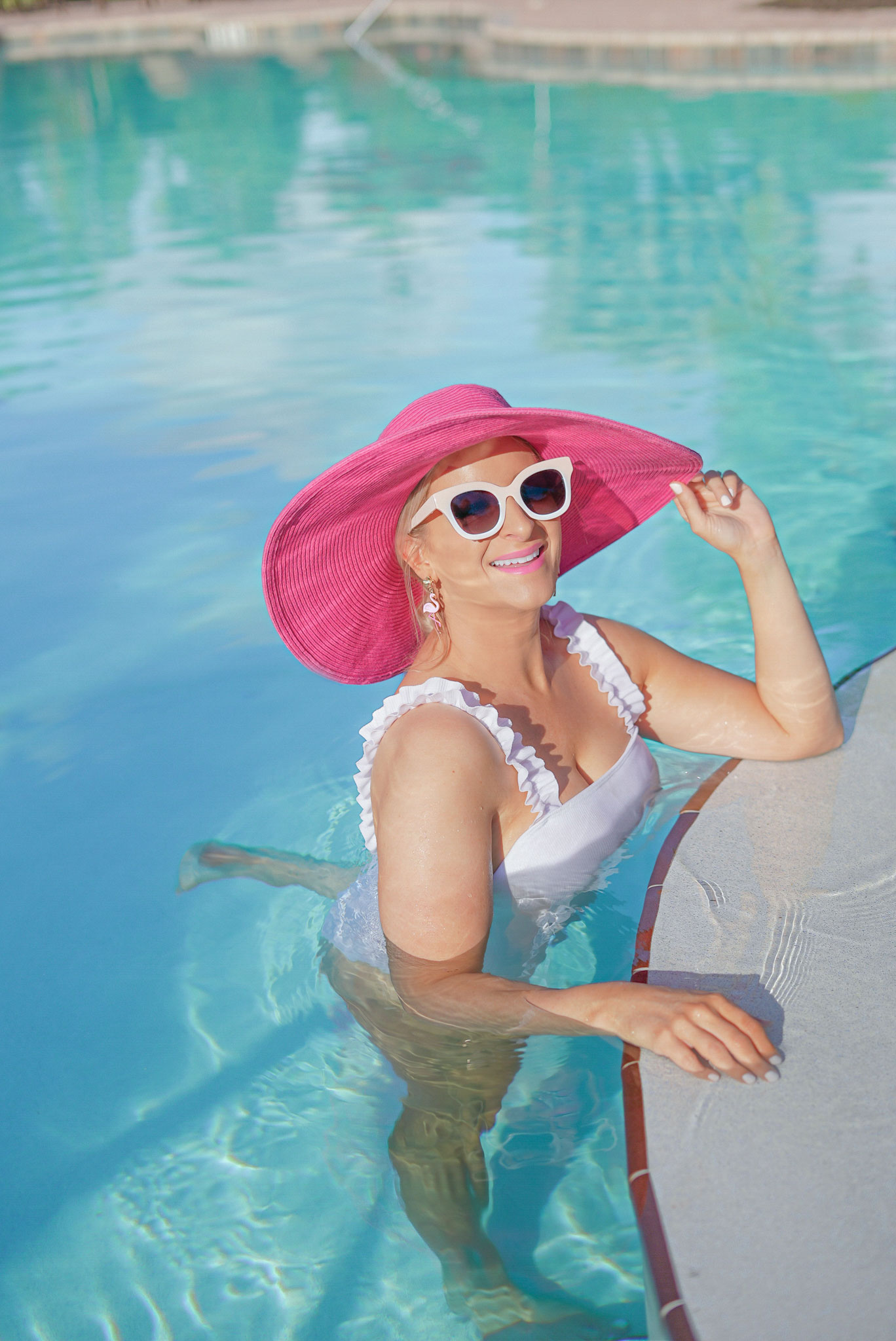 Florida Blogger, Jill DiGioia, The Lovely Flamingo wears pink flamingo earrings from her new beach earring collection along with pink sunglasses and a pink straw hat.