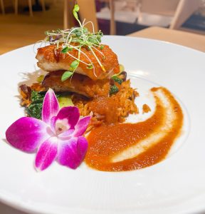 A plate of food with some sauce and flowers