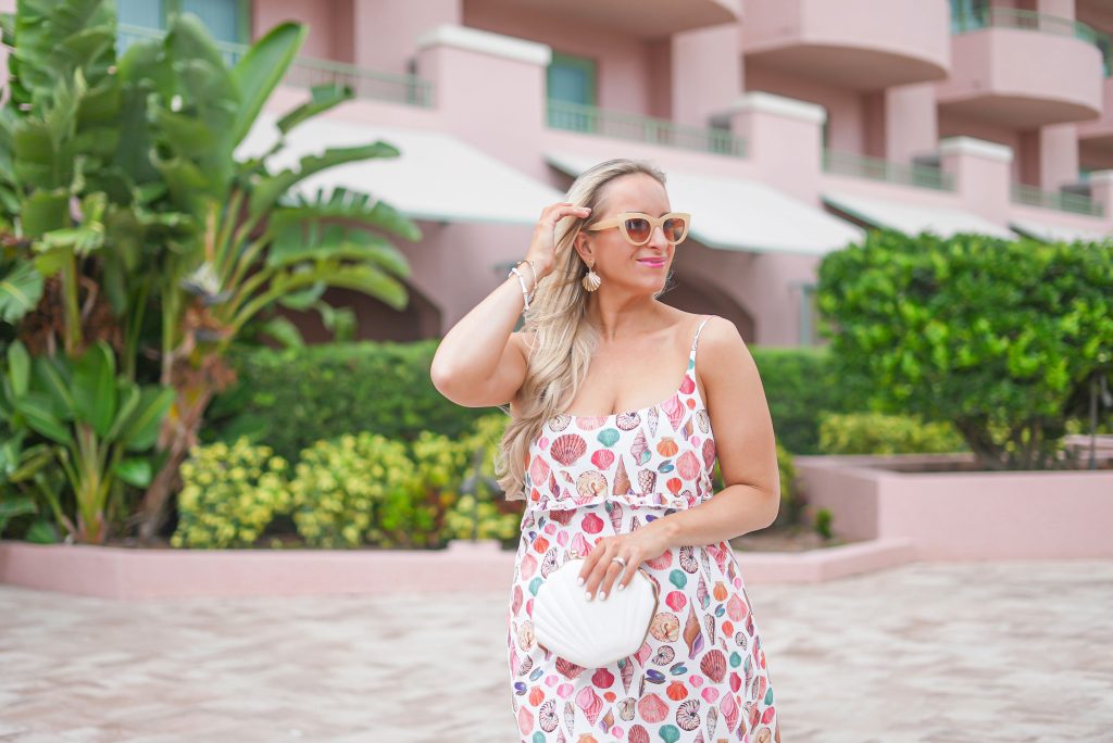 Florida Blogger, The Lovely Flamingo, wears a shell dress with shell earrings, a shell bag, and tan cat eye sunglasses.