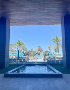 A pool with water jets and palm trees in the background.