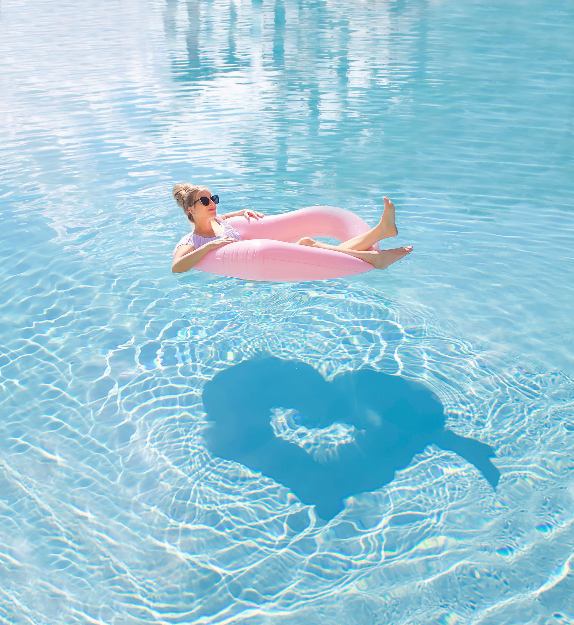 Florida Blogger, The Lovely Flamingo floats on a heart shaped float in a pool with a heart shaped reflection in the water.