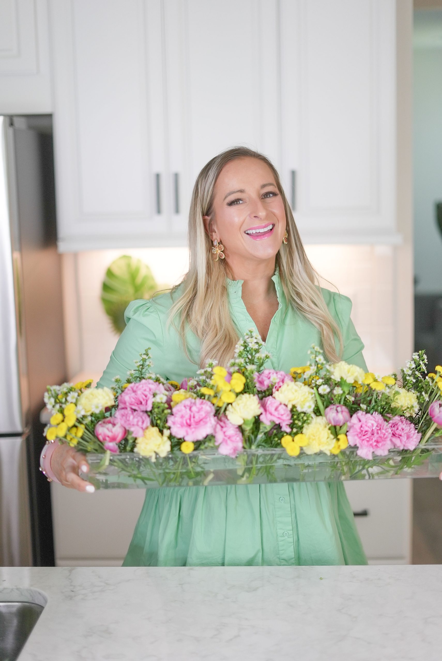 A woman holding a tray of flowers in her hands.